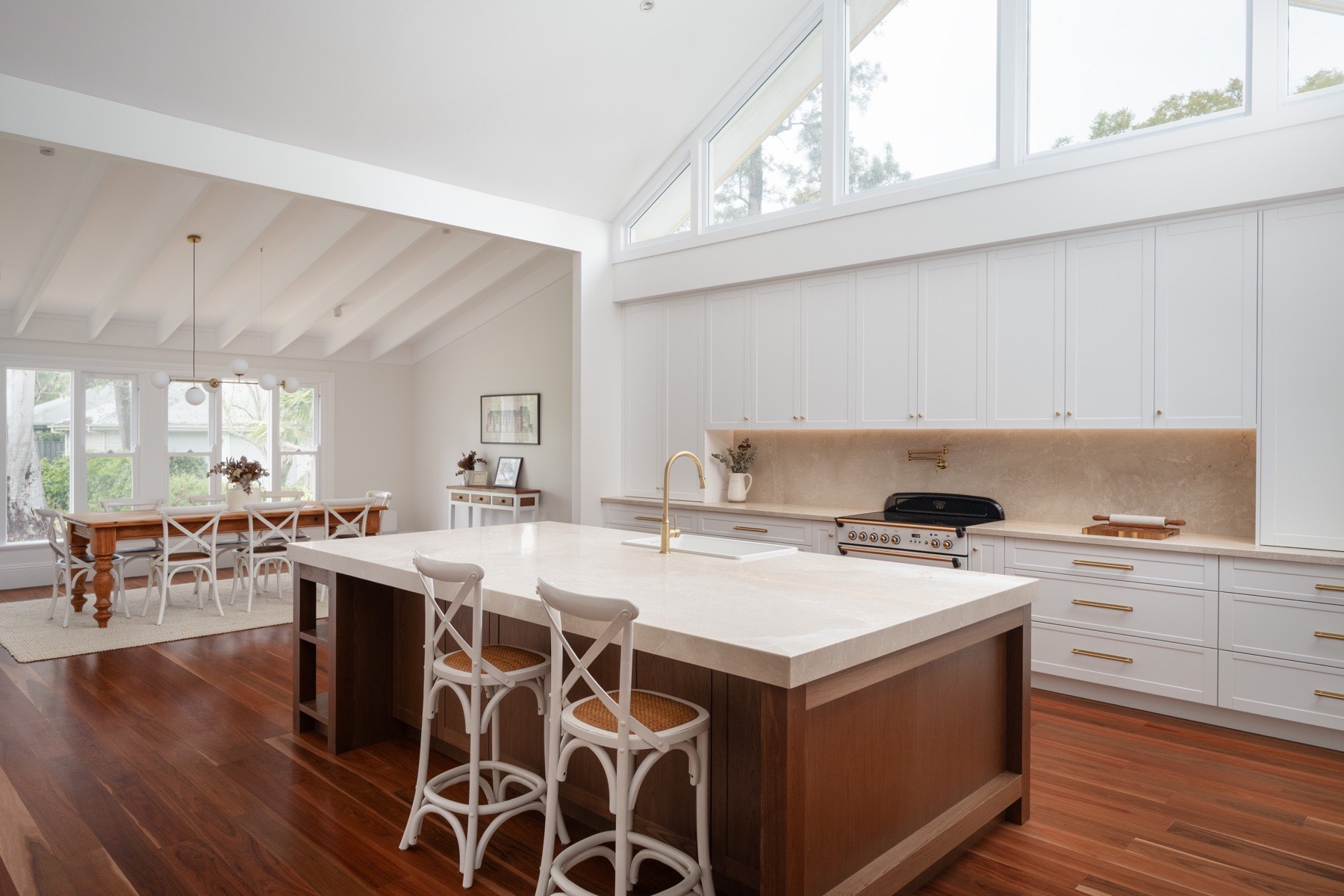 Cathedral-ceiling kitchen with a timber island and stone top in Bolwarra
